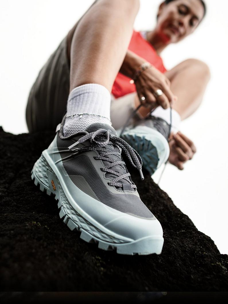 Close-up of model sitting on a rock, tying their Tellurix Titanium Outdry shoe.