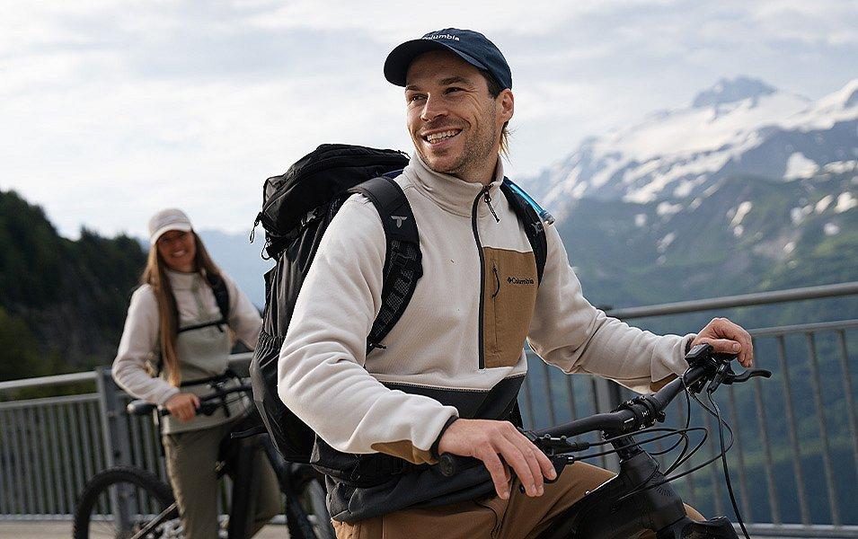A man and a woman enjoy a bike ride; they are enjoying their excursion because they have warm fleece pullovers to keep them warm.