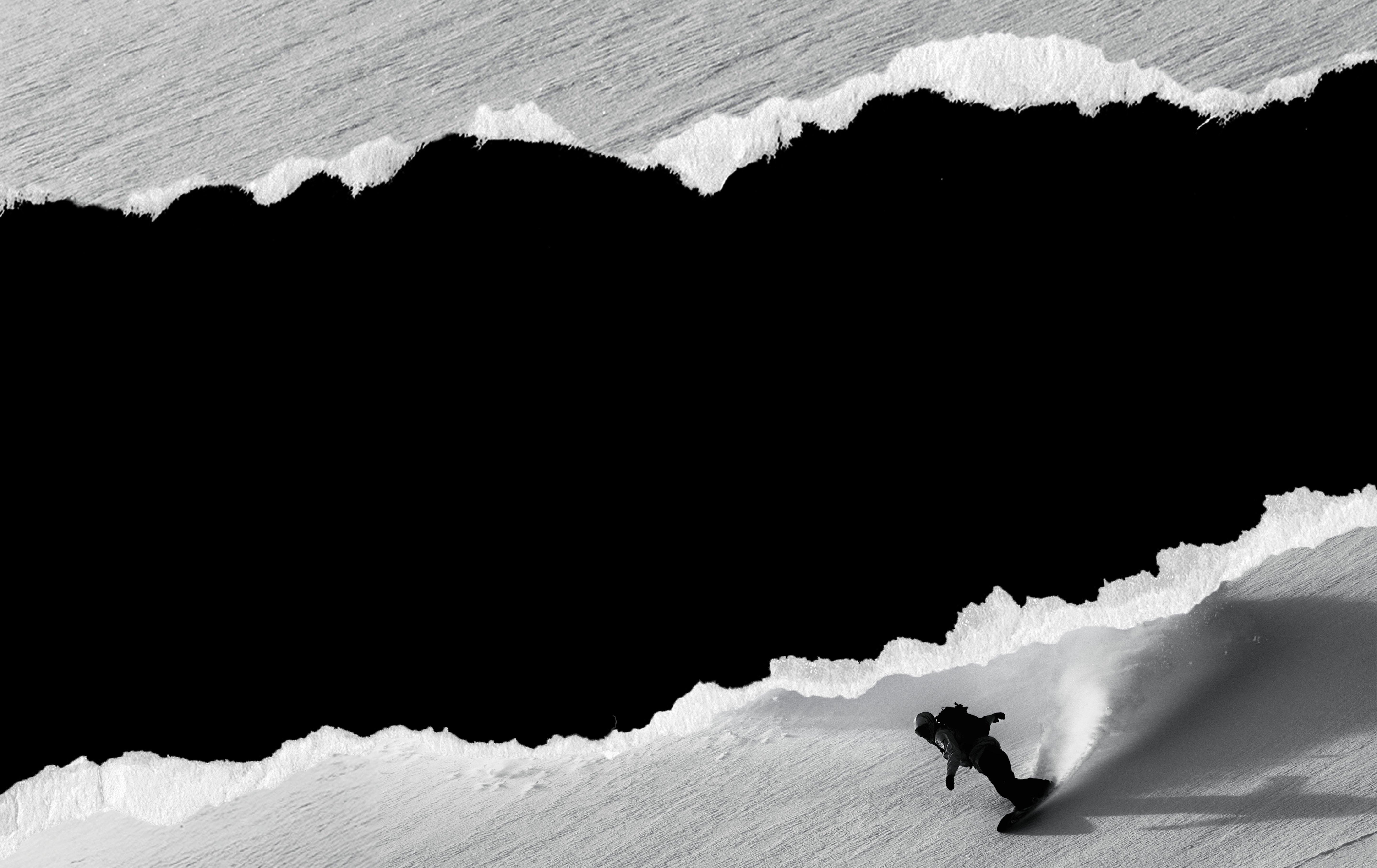 Snowboarder carving down a snowy slope in black and white artistic composition with dramatic contrast.