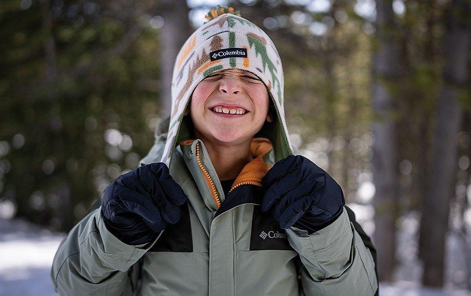 An insulated jacket, winter hat, and warm gloves keep this young skier happy and cozy. 