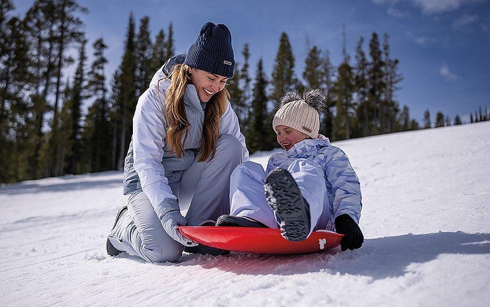 Snow doesn’t stop this woman and child from enjoying sledding fun, thanks to their essential winter apparel.