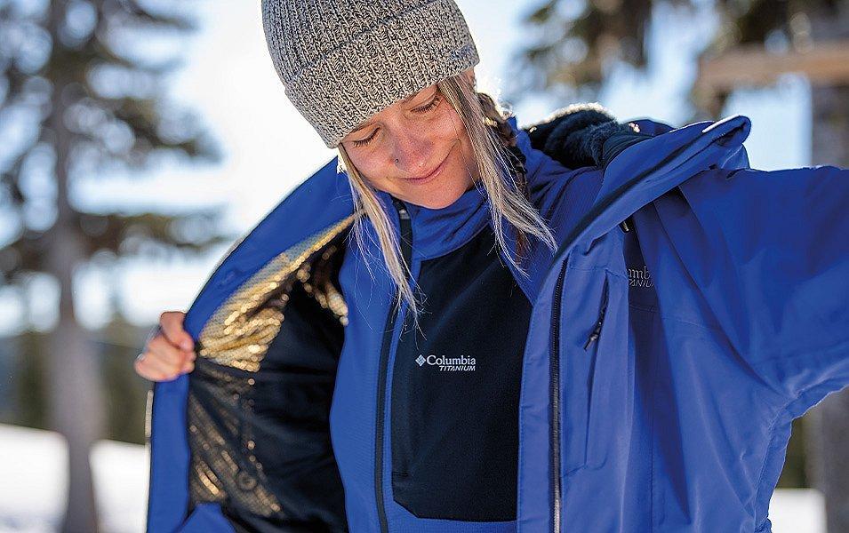 A backcountry skier removes her outer layer before beginning the uphill climb.