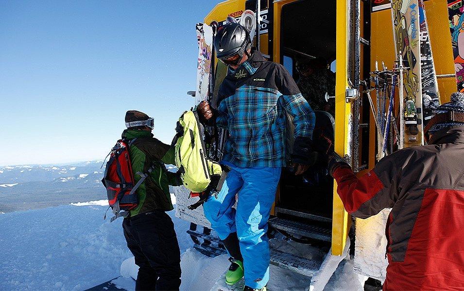  After a cozy ride up the mountain in a snowcat, skiers exit, carrying their daypacks. 