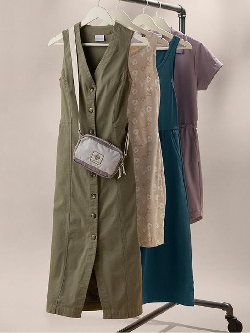 Four dresses hanging on a clothing rack with a small crossbody bag displayed on the olive dress.