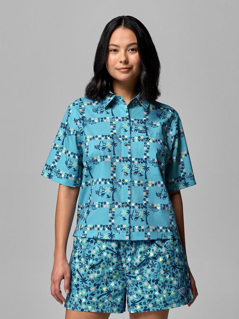 Woman wearing turquoise short-sleeve button-up shirt and matching shorts with tropical floral print.