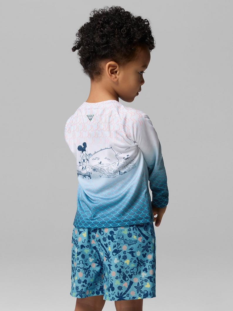 Child wearing long-sleeve swim shirt with mermaid scale gradient and matching swim shorts with sea life print.