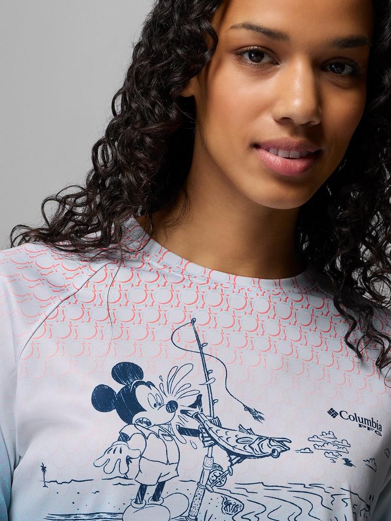 Woman with curly hair wearing a graphic tee featuring a character fishing on a beach.