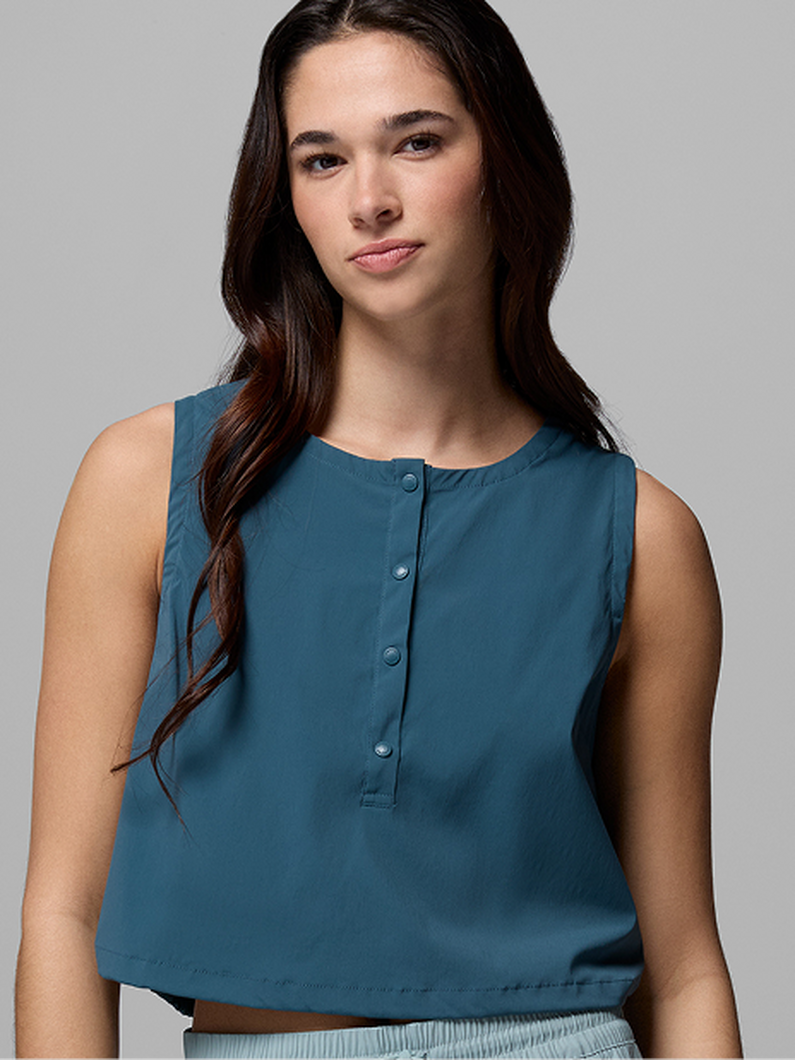 Woman wearing a teal sleeveless blouse with button-front placket detail.