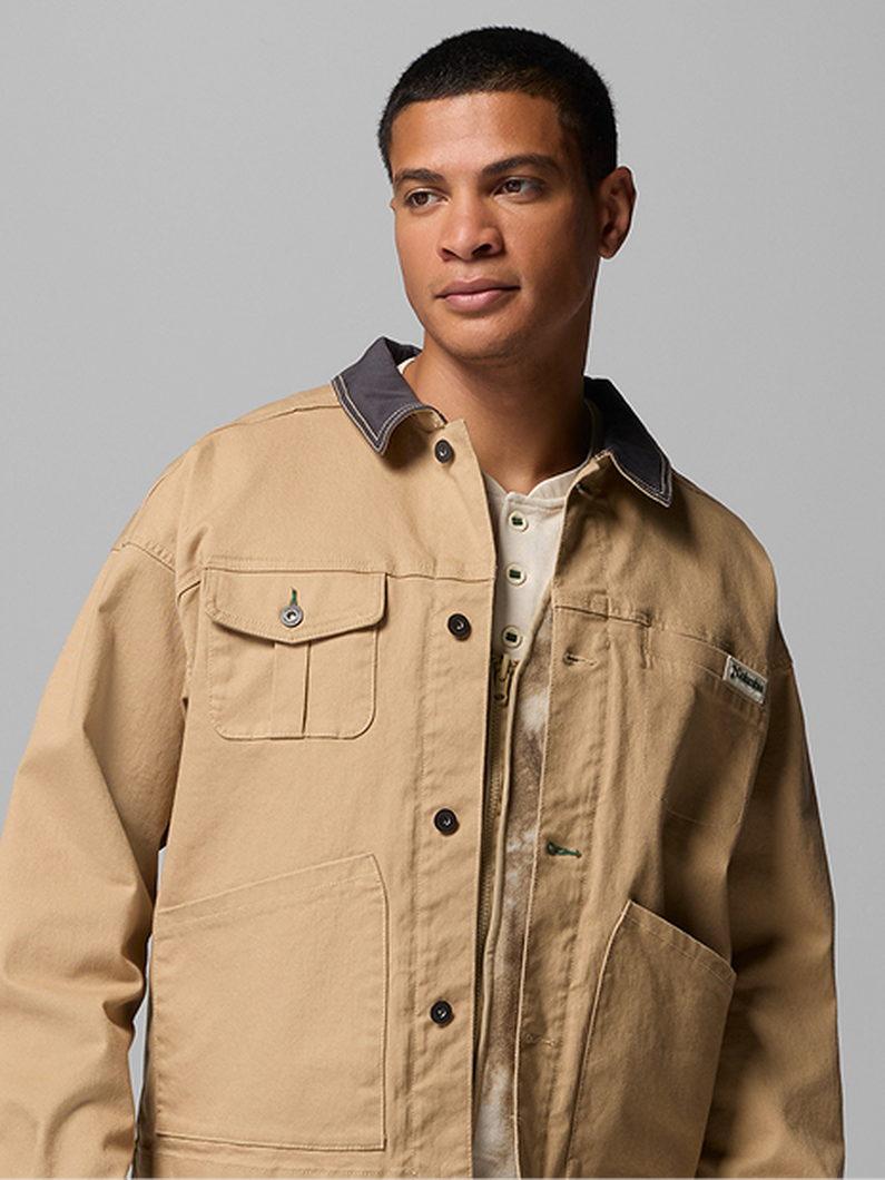 Man wearing a tan utility jacket with chest pockets and dark contrast collar, shown partially open.