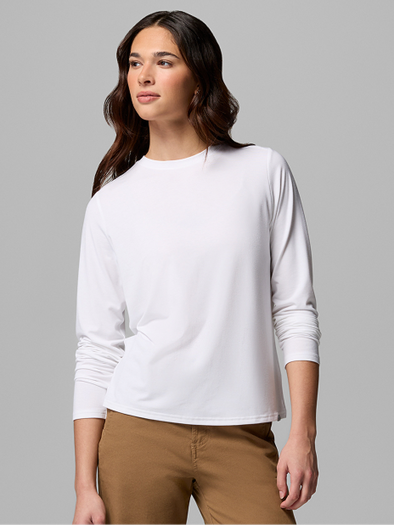 Woman wearing white long-sleeve crew neck top with tan pants.