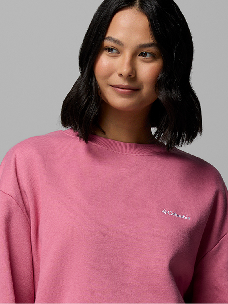 Woman wearing a pink crew neck sweatshirt with relaxed fit and long sleeves.