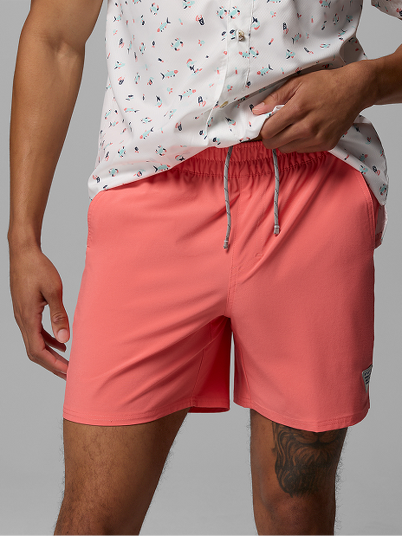 Person wearing coral elastic waistband shorts with drawstring and a white patterned t-shirt.