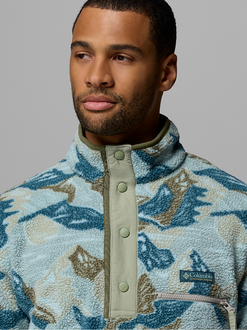 Man wearing a fleece pullover with blue and tan camouflage pattern and snap button placket.