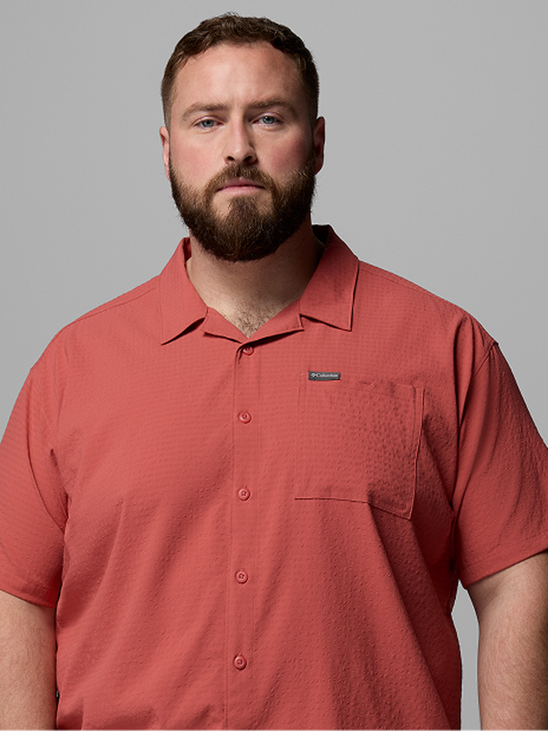 Man wearing coral short-sleeve button-up shirt with chest pocket facing forward.