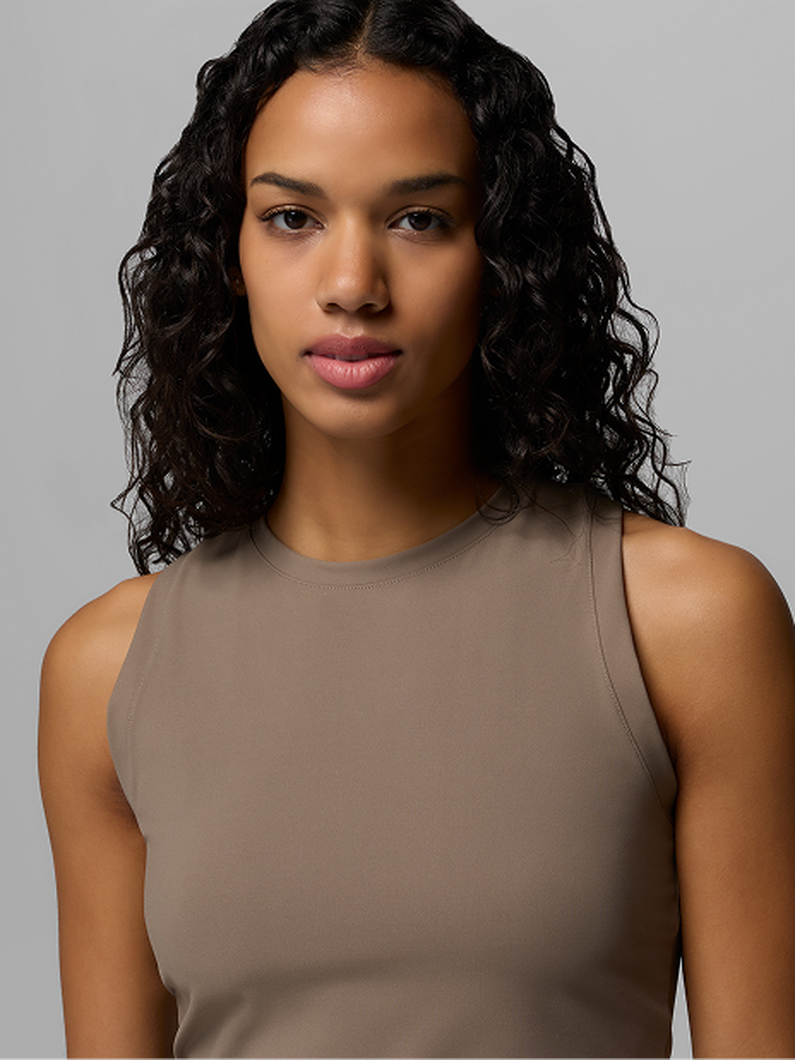 Model wearing a taupe sleeveless crew neck top with a fitted silhouette.