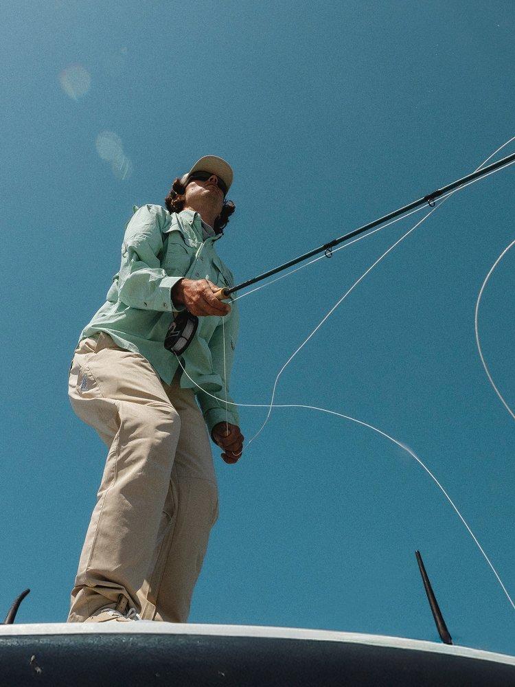 Women with green fishing vest over a long sleeve orange shirt.