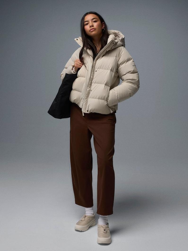 A woman wearing a white puffer jacket and holding a black tote.