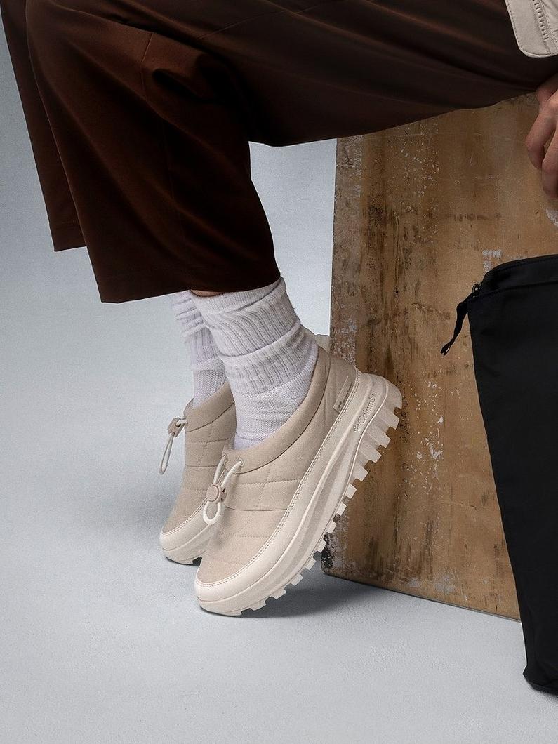 Close-up of a woman's white slip-on shoes.