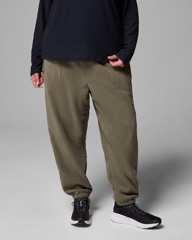 Waist-down image of a woman wearing dark green pants and sneakers.