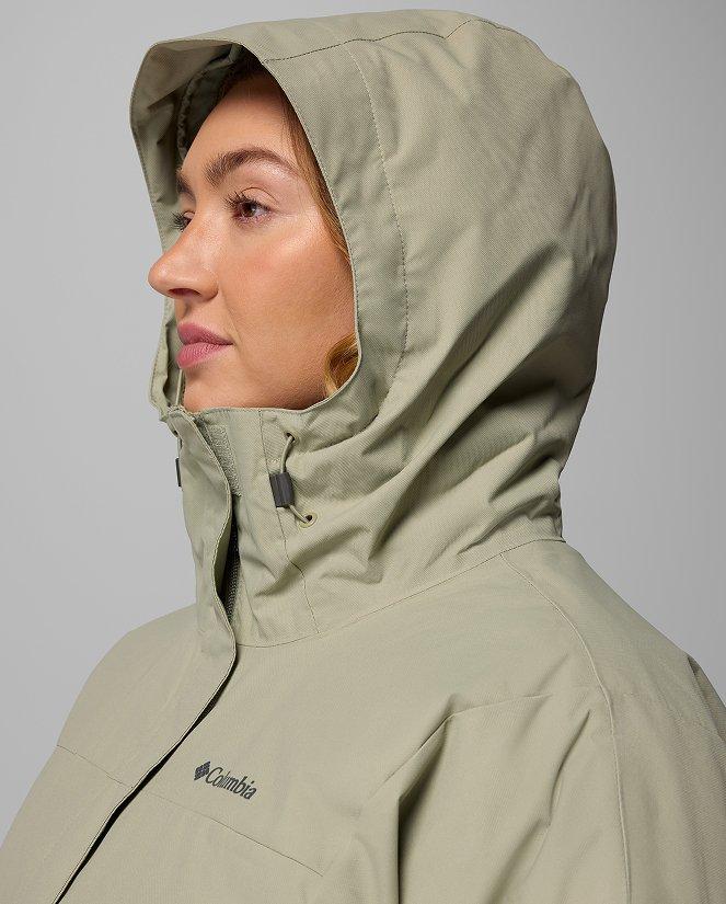 A woman wearing a green rain jacket with the hood up.