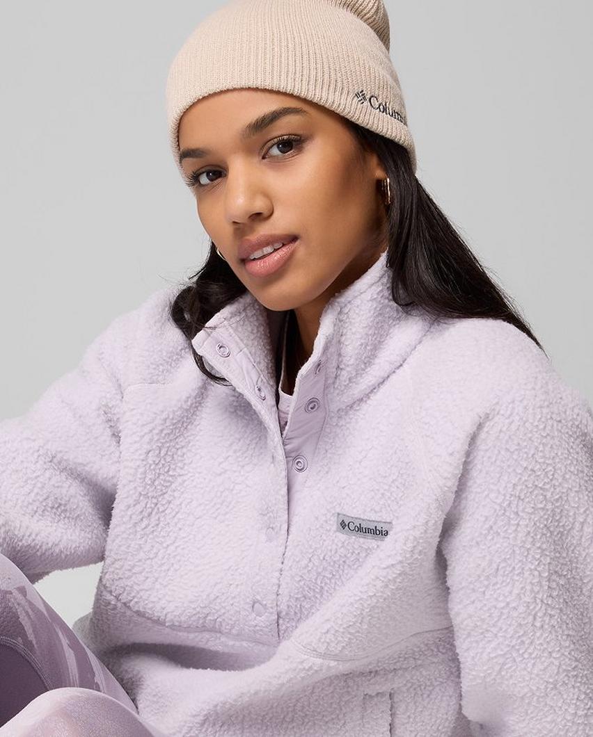 A woman wearing a purple fleece pullover with a cream beanie.