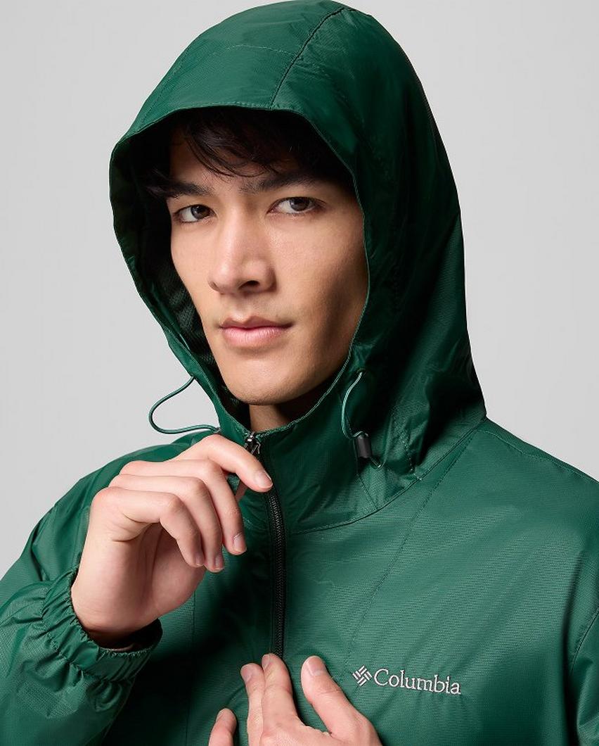 A man wearing a green rain jacket with the hood up.