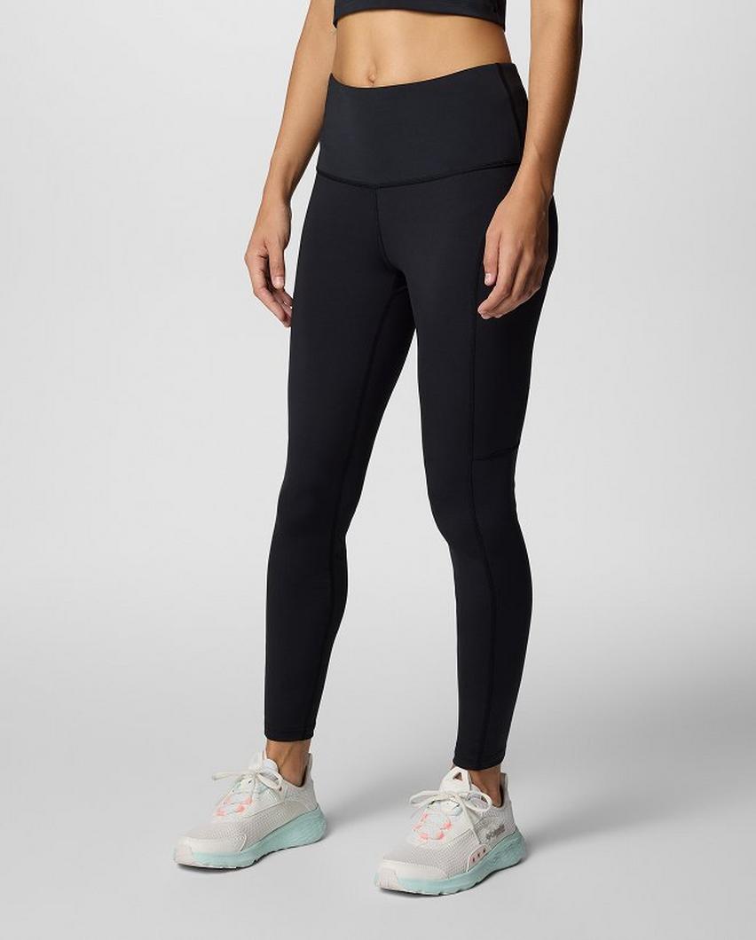 Waist-down image of a woman wearing black leggings and sneakers.