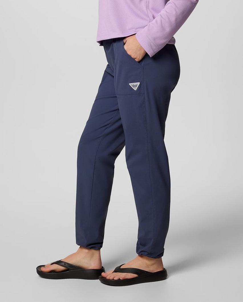 Waist-down image of a woman wearing navy PFG pants and flip flops.