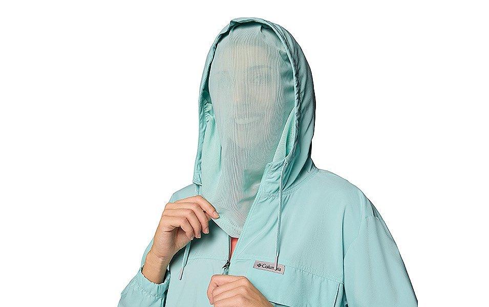 A woman wears a long-sleeve jacket featuring sheer netting that extends from the hood to her neck.