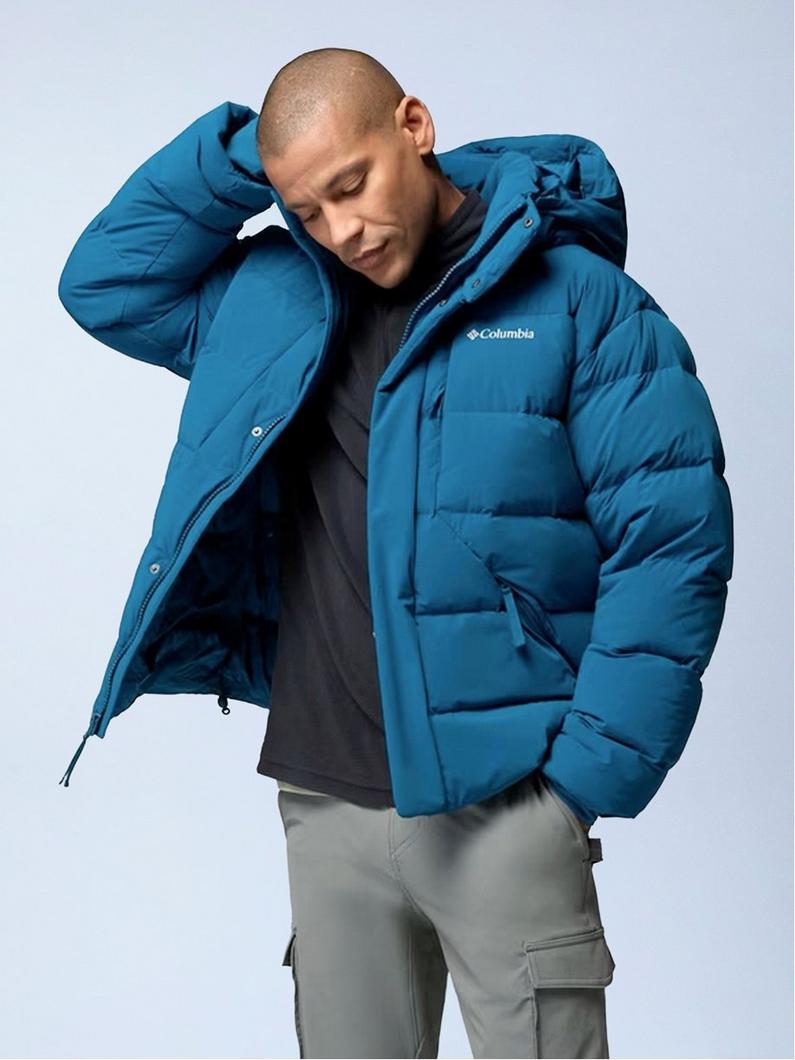 Man wearing teal blue puffer jacket with hood, paired with gray cargo pants and dark hoodie.