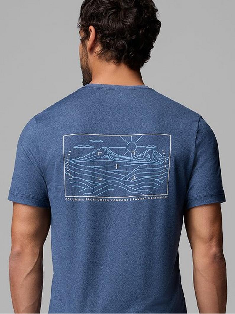Back view of man wearing blue t-shirt with white line art graphic of mountains, sun, and waves.