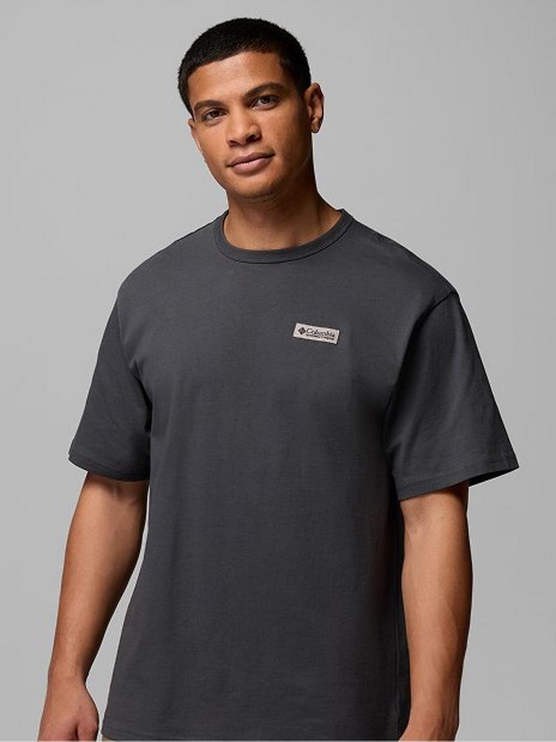 Man wearing a charcoal gray short-sleeve crew neck t-shirt with small chest logo patch.