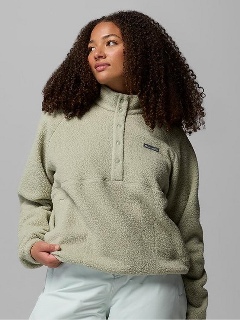 Woman wearing sage green fleece quarter-zip pullover with white pants, looking upward and to the side.