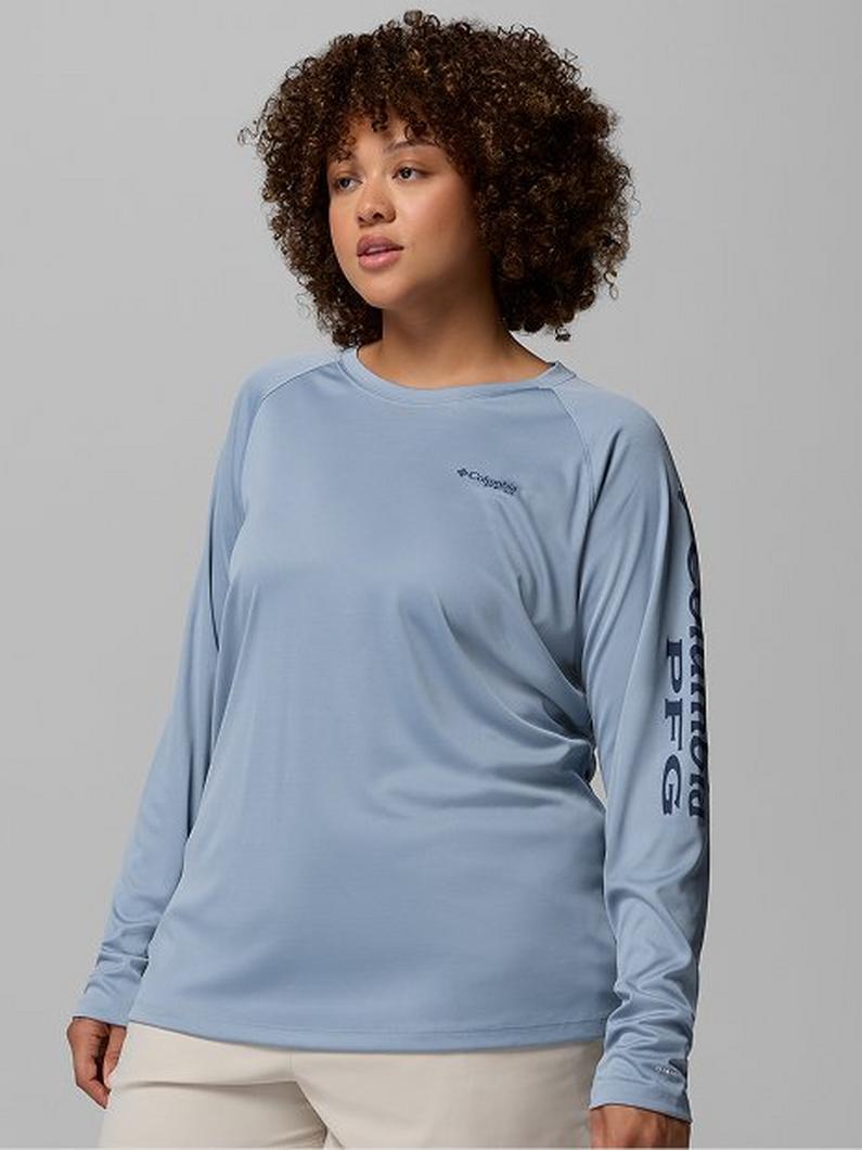 Woman wearing a light blue long-sleeve performance shirt with text graphic on the sleeve.