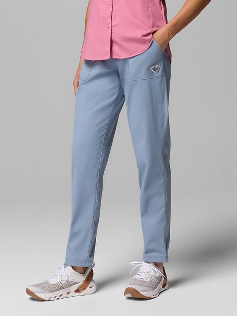 Model wearing light blue casual pants with hand in pocket, paired with pink top and white sneakers.