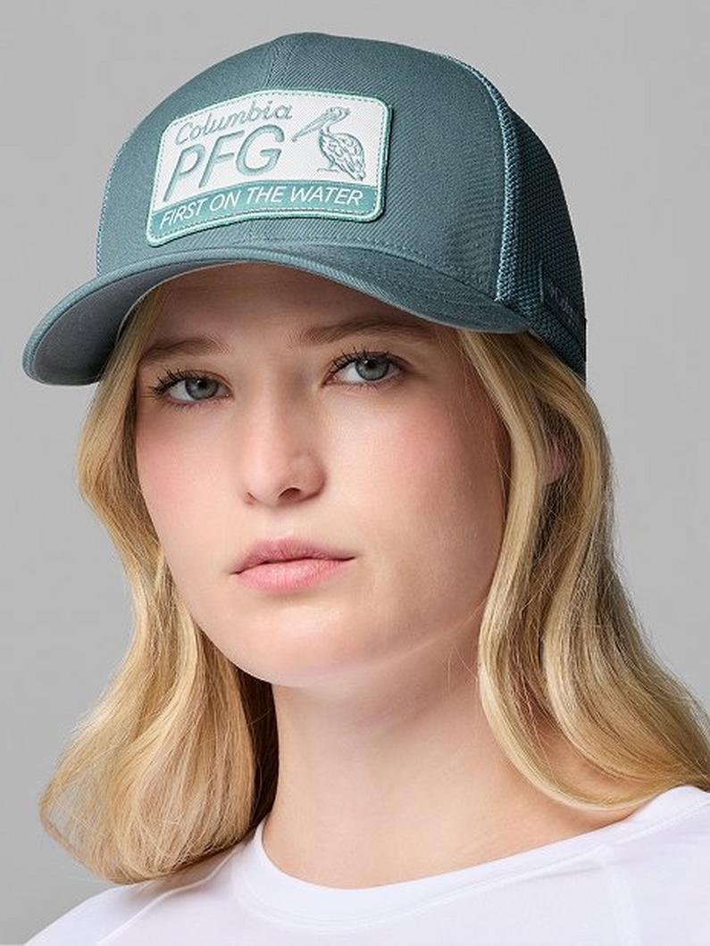 Teal mesh trucker cap with white patch reading "Columbia PFG ARISE ON THE WATER" worn by a woman.
