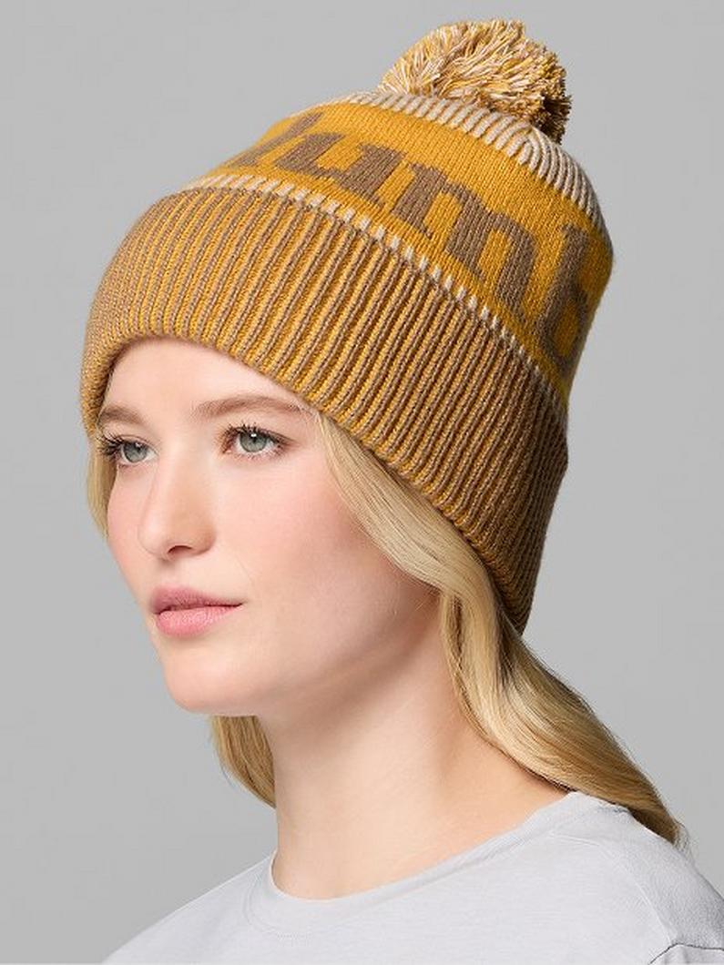 Mustard yellow ribbed knit beanie with pom-pom on top, modeled by a woman with blonde hair.
