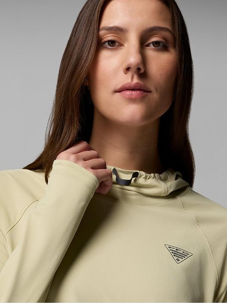 Woman wearing a pale yellow athletic pullover with funnel neck and small logo detail on chest.