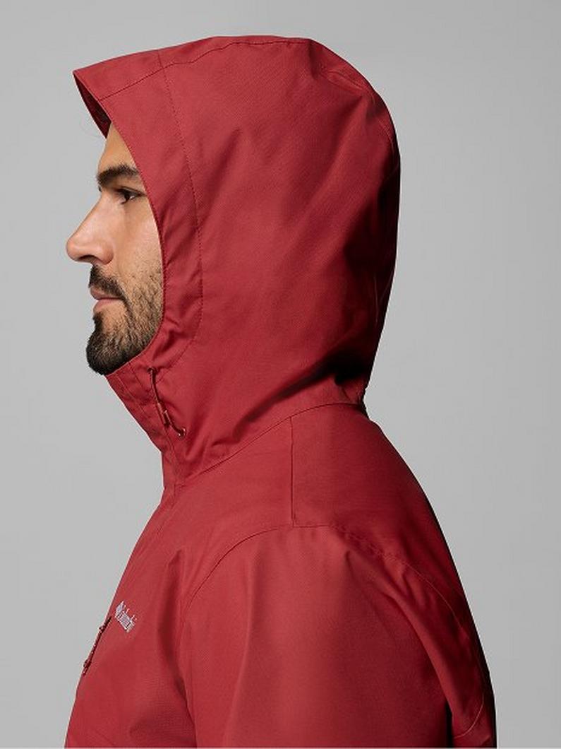 Side profile of a man wearing a red hooded jacket with the hood up.