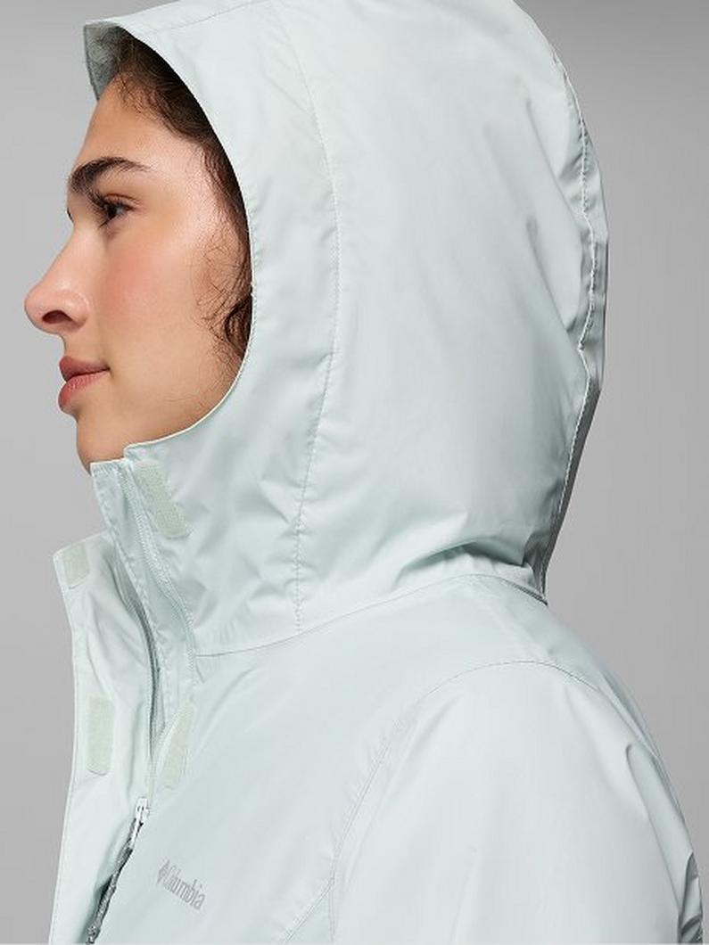 Side profile of a woman wearing a light blue hooded jacket with zipper detail.