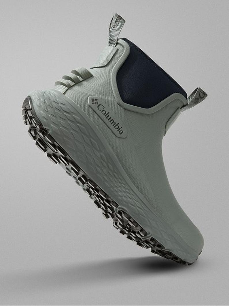 Sage green slip-on shoe with navy collar and pull tabs, featuring textured sole with chain-link tread pattern.