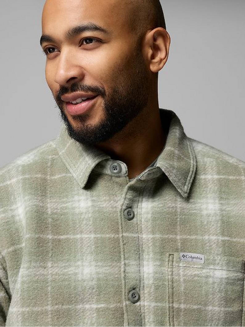 Man wearing a sage green and white plaid flannel shirt with collar and button front closure.