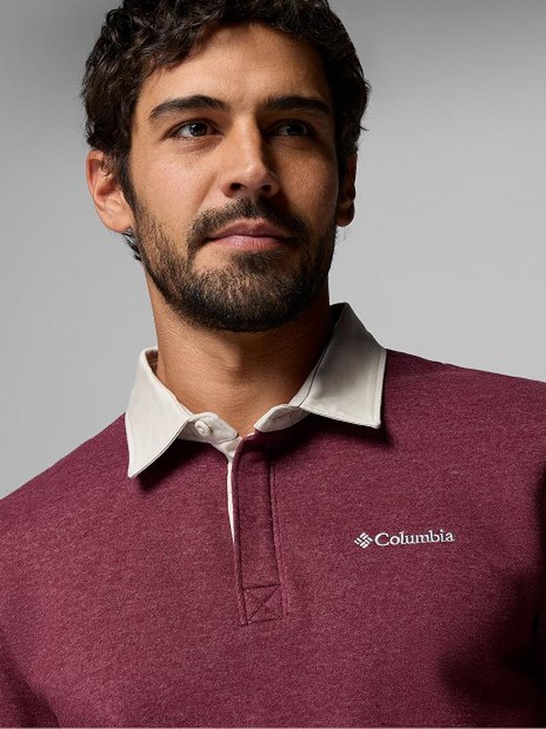 Man wearing a burgundy rugby polo shirt with white collar, looking upward in a portrait pose.
