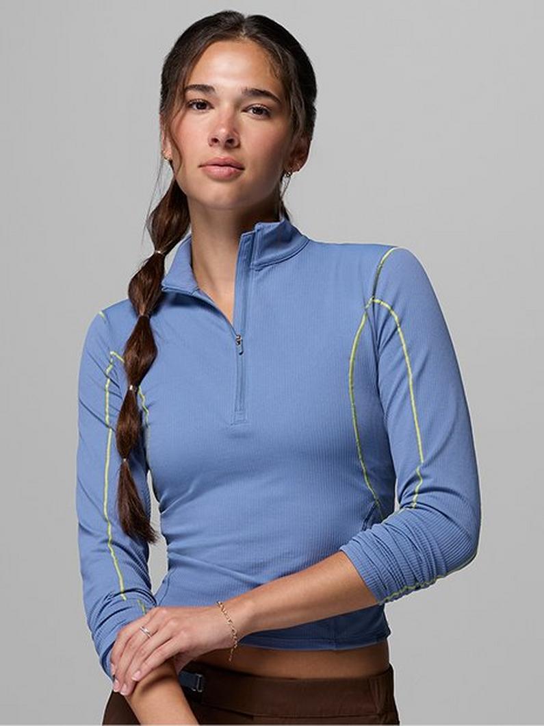 Woman wearing blue half-zip athletic top with ribbed texture and contrast piping detail.