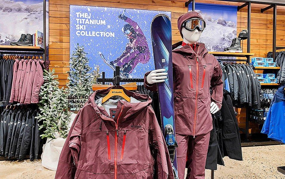 Intérieur d'un espace de vente au détail Columbia avec un mannequin habillé en tenue de neige et des portants de vêtements.
