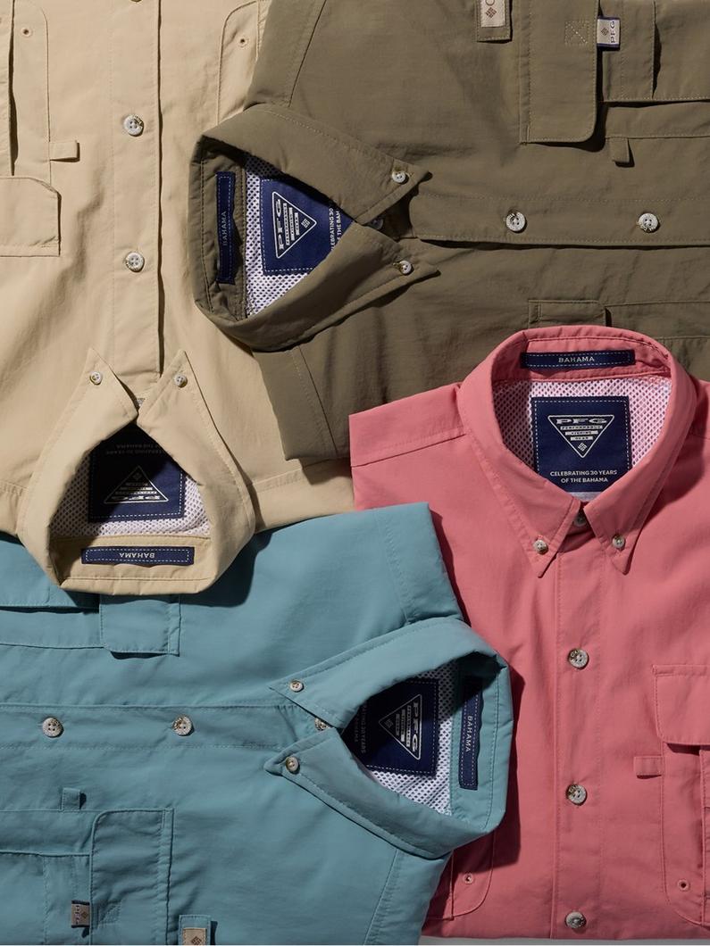 Four folded button-down shirts in olive, tan, coral pink, and light blue with chest pockets displayed flat.