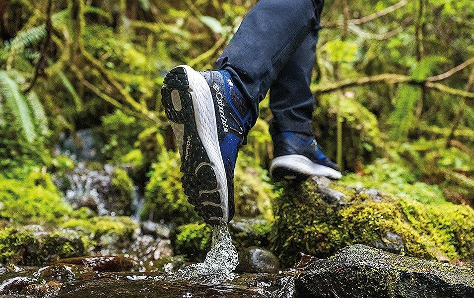 Close up of a person in Columbia Sportswear shoes walking through a stream.