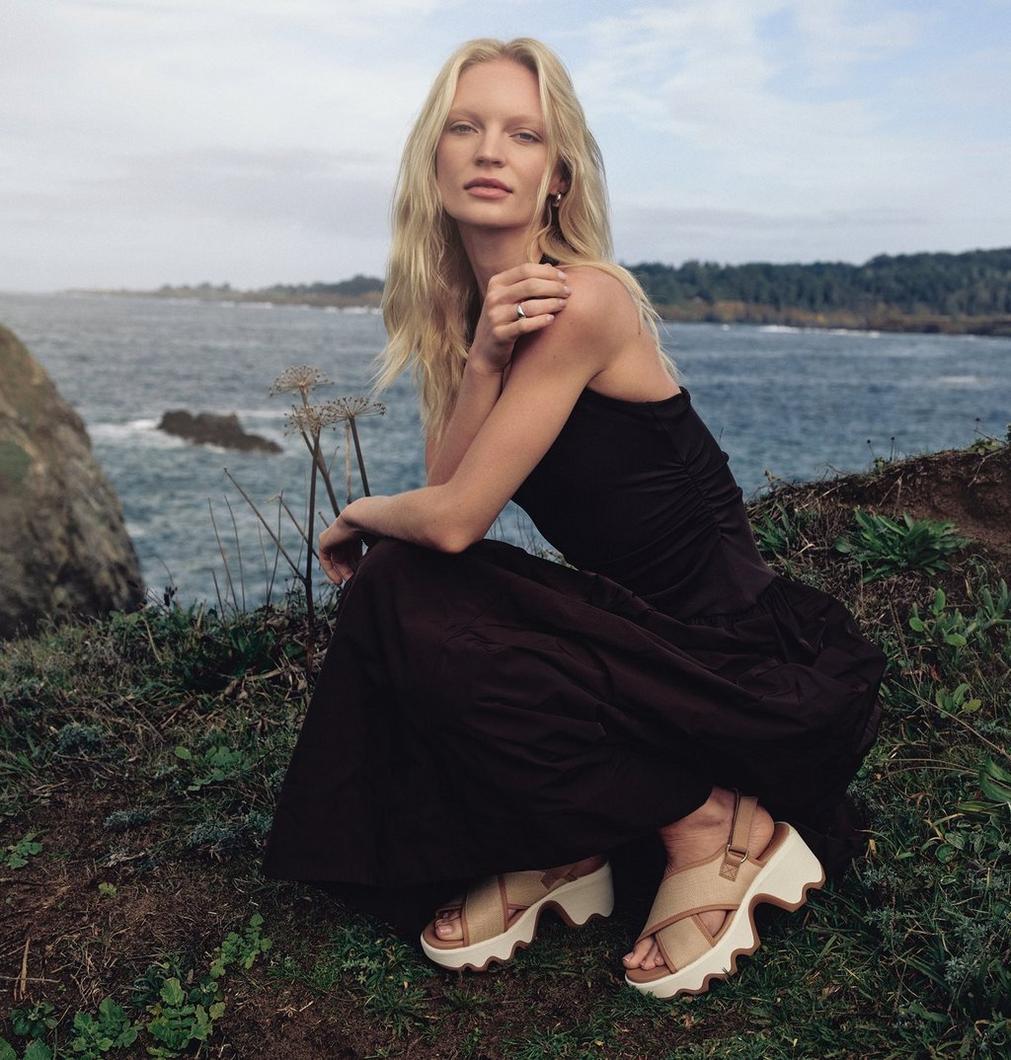 Women in a black dress and tan sandles.