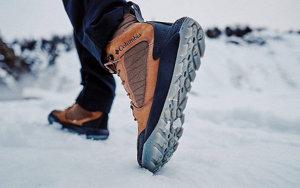 A person in Columbia Sportswear Snow boots walks across a snowy clearing. 