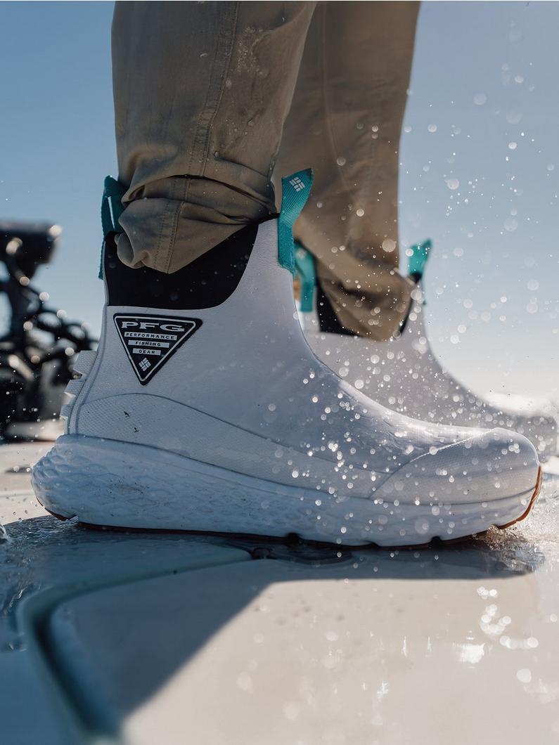 Gray waterproof boots with teal straps being worn while walking through shallow water.